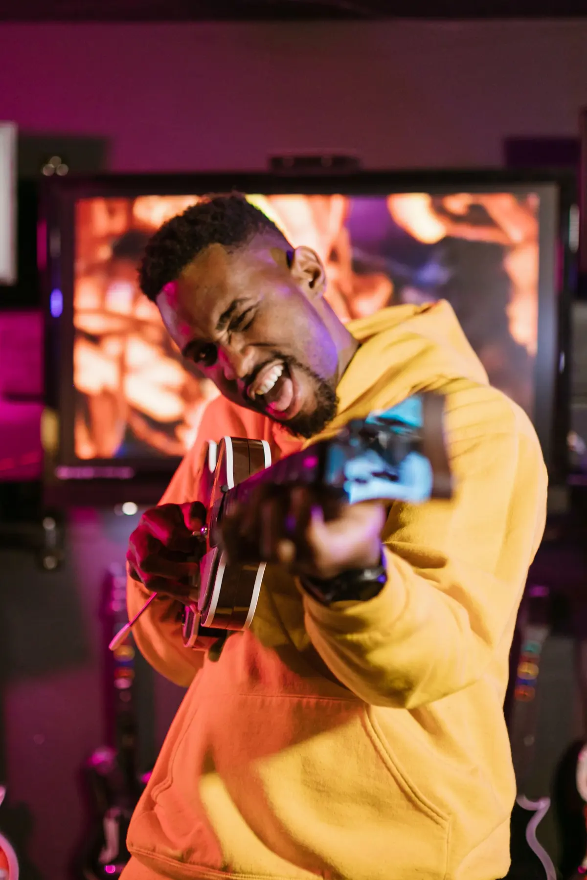 A gamer in a yellow hoodie grinning and celebrating in the lounge